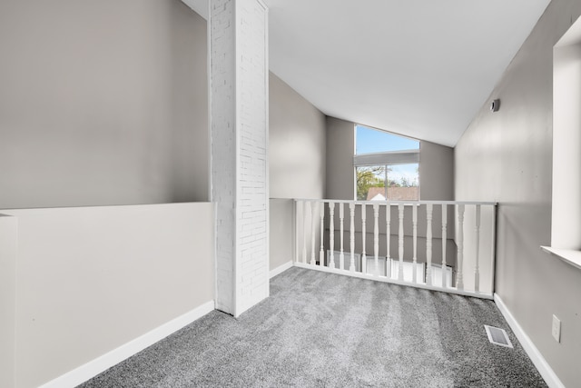 carpeted empty room featuring lofted ceiling and baseboards