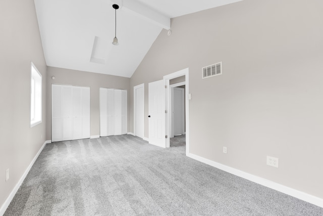 unfurnished bedroom with two closets, beamed ceiling, high vaulted ceiling, carpet, and baseboards