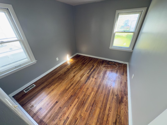 unfurnished room featuring plenty of natural light, wood finished floors, and baseboards