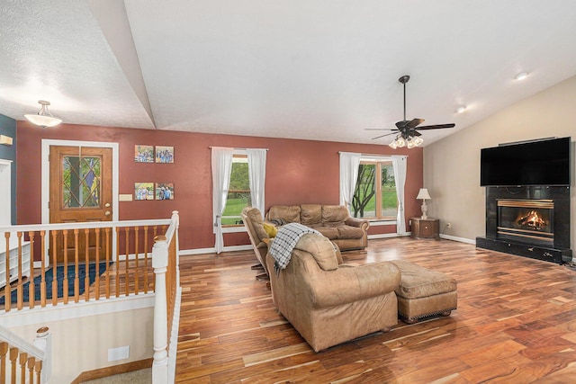 2269 W Liberty Rd, Clarklake, MI 49234 - living area featuring vaulted ceiling, wood finished floors, a ceiling fan, baseboards, and a glass covered fireplace
