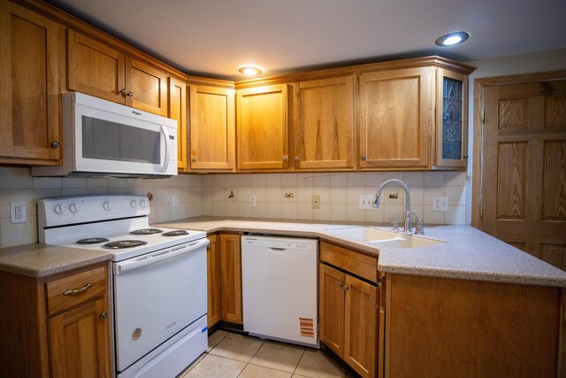 kitchen with white appliances, a sink, tasteful backsplash, light countertops, and brown cabinets