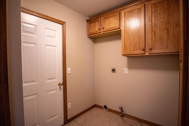 laundry room featuring cabinet space, baseboards, hookup for an electric dryer, and light tile patterned flooring
