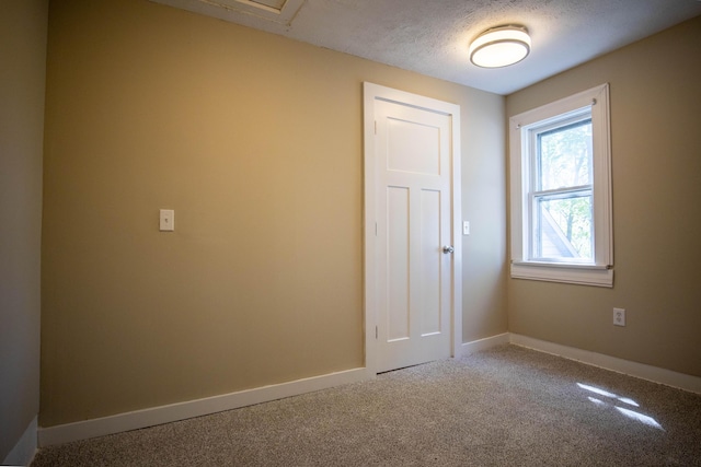 carpeted spare room featuring baseboards and a textured ceiling