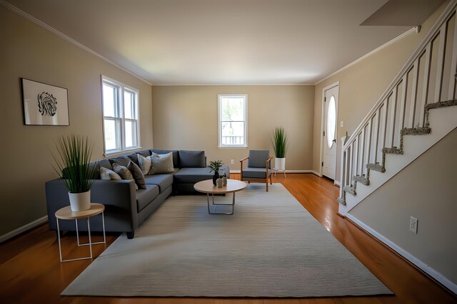 living area with ornamental molding, wood finished floors, stairs, and baseboards