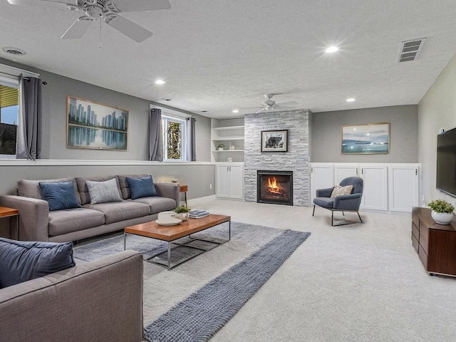 6927 Drumlin Dr, Zeeland, MI 49464 - living area featuring ceiling fan, a textured ceiling, carpet floors, built in shelves, and a stone fireplace