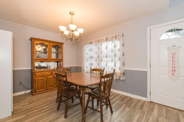 dining room featuring a chandelier, light wood-style flooring, and baseboards