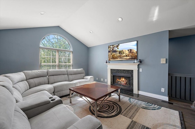 living room with wood finished floors, lofted ceiling, a fireplace with flush hearth, and recessed lighting