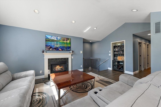 living room with wood finished floors, vaulted ceiling, recessed lighting, a premium fireplace, and baseboards