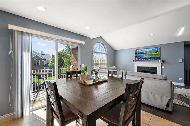 dining space with vaulted ceiling, a fireplace, recessed lighting, baseboards, and light wood-style floors