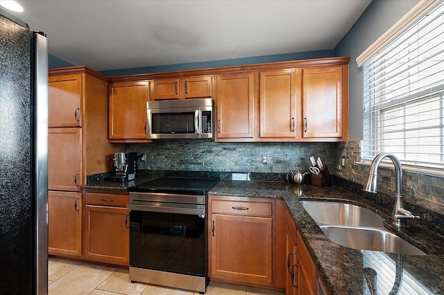 kitchen with appliances with stainless steel finishes, a sink, brown cabinets, and backsplash