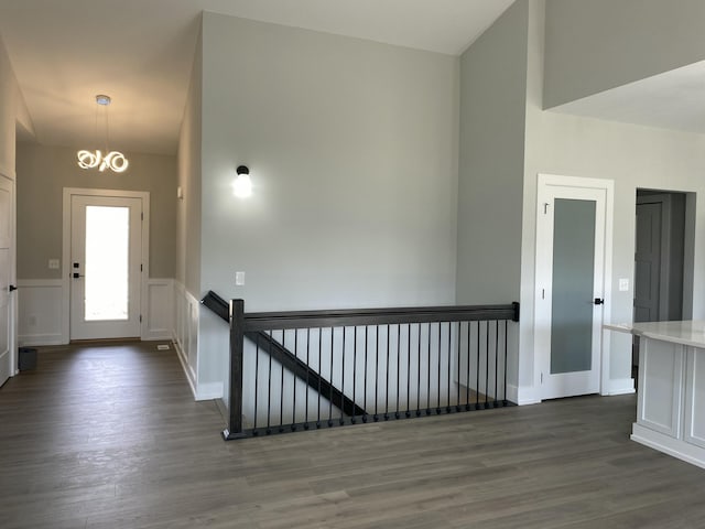 foyer entrance featuring dark wood-style floors, a chandelier, and baseboards