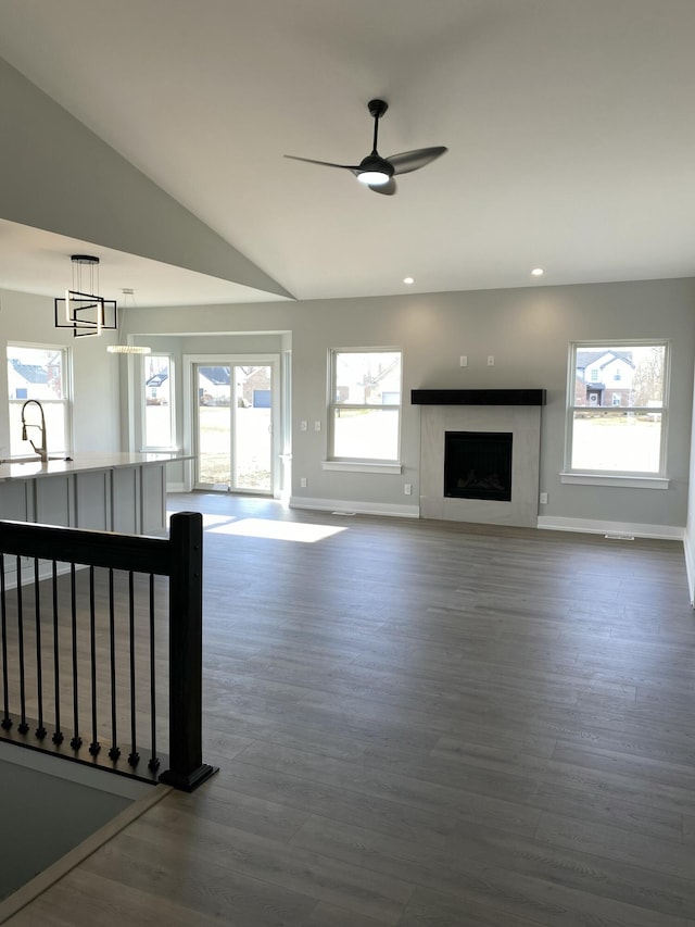 unfurnished living room featuring baseboards, dark wood-type flooring, a ceiling fan, a premium fireplace, and recessed lighting