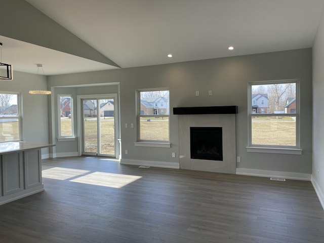 unfurnished living room with dark wood-style floors, healthy amount of natural light, baseboards, a fireplace, and lofted ceiling