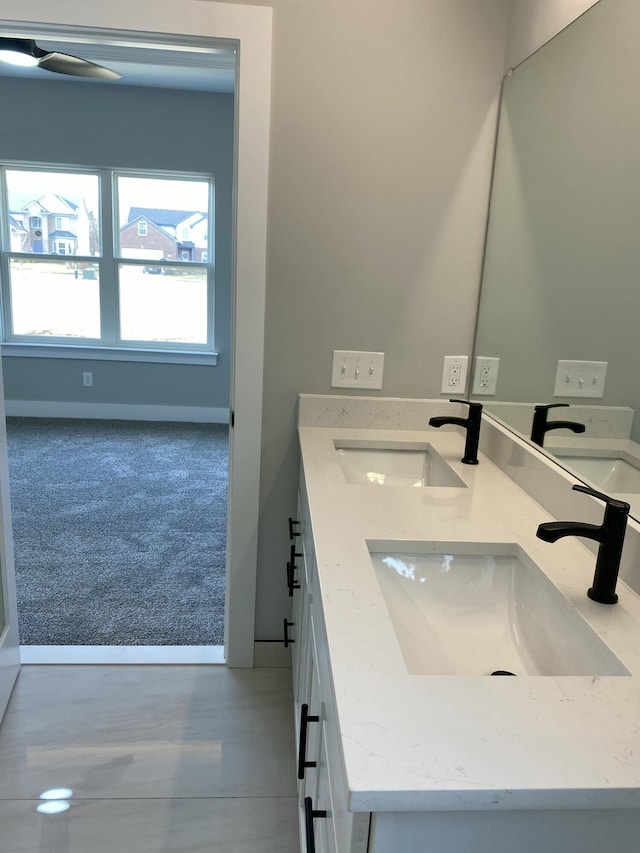 bathroom with baseboards and double vanity