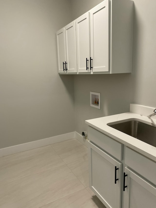 washroom with hookup for a washing machine, cabinet space, baseboards, and light tile patterned floors