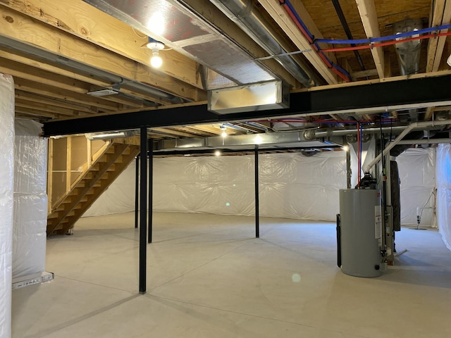 unfinished below grade area featuring gas water heater and stairway