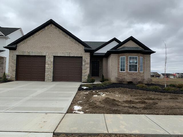 view of front of house with a garage, concrete driveway, and brick siding