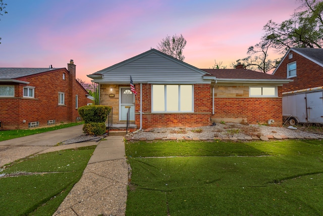 bungalow featuring brick siding and a yard