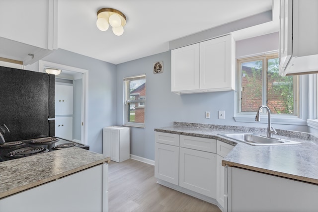 kitchen with a sink, white cabinetry, plenty of natural light, and black / electric stove