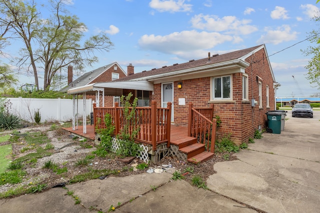 view of front of home featuring brick siding, fence, a chimney, and a wooden deck