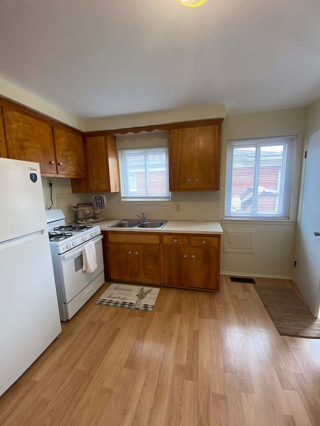 657 Highland Ave, Lincoln Park, MI 48146 - kitchen with white appliances, a sink, brown cabinetry, and light wood finished floors