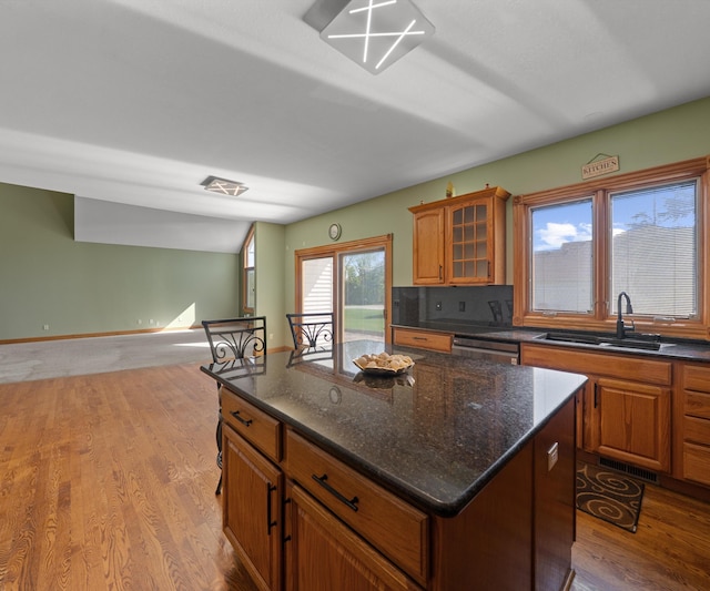 kitchen featuring a sink, light wood-type flooring, a center island, and brown cabinets