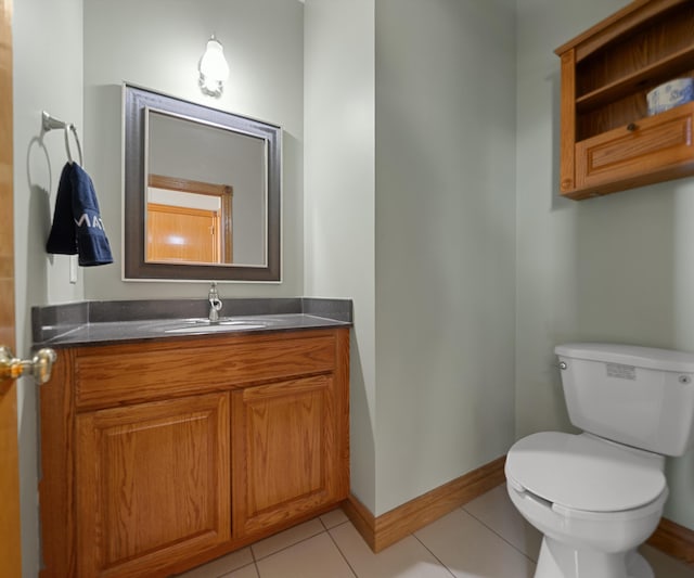 bathroom with toilet, vanity, tile patterned flooring, and baseboards
