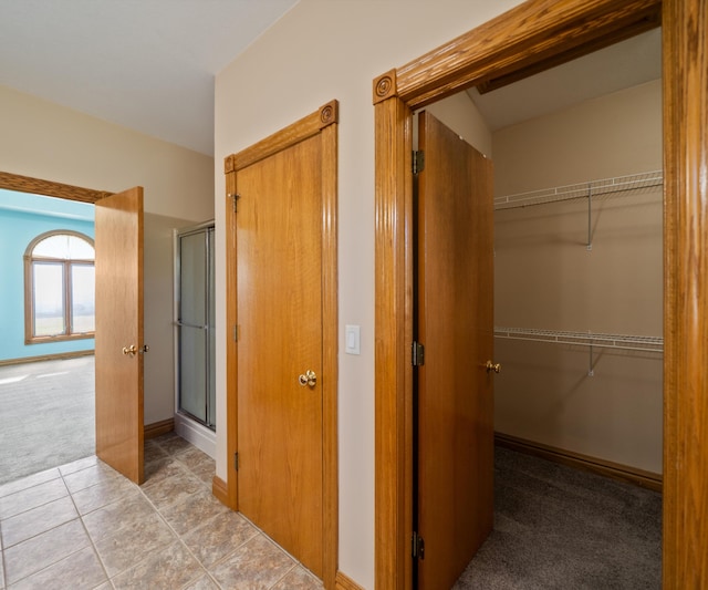 hallway with carpet flooring and tile patterned flooring