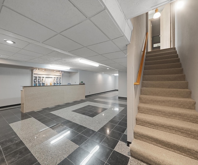 finished below grade area featuring granite tiled floors, stairway, baseboards, recessed lighting, and a community bar