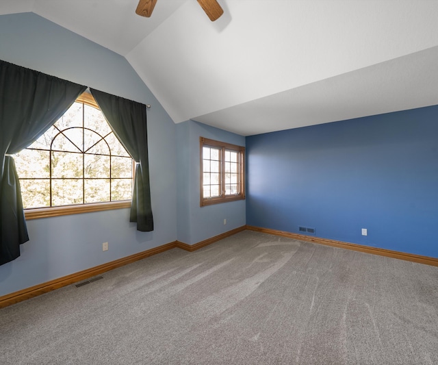 carpeted spare room featuring lofted ceiling, ceiling fan, and baseboards
