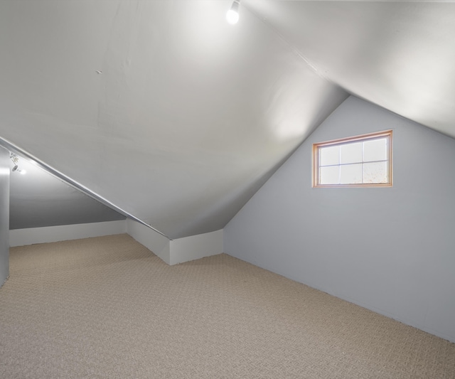 additional living space with carpet flooring and lofted ceiling
