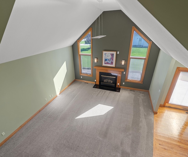 bonus room with healthy amount of natural light, baseboards, vaulted ceiling, a fireplace with flush hearth, and wood finished floors