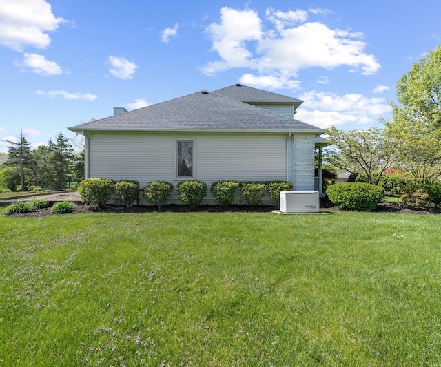view of home's exterior with a lawn and roof with shingles