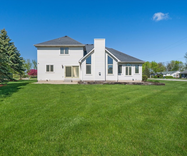 back of house with a lawn, a chimney, and a patio