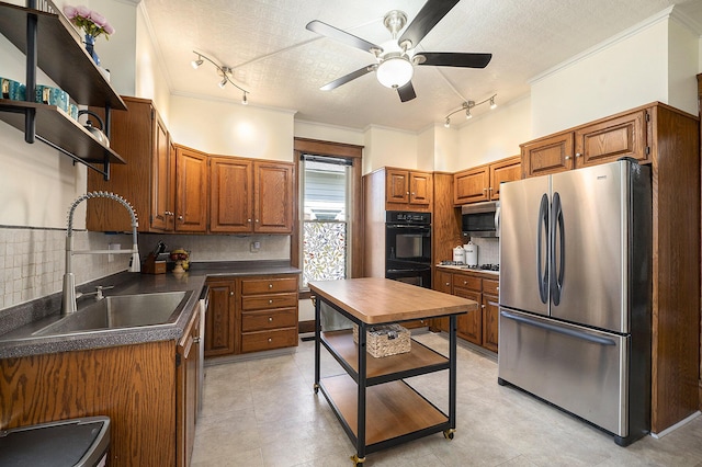 210 E St, Three Rivers, MI 49093 - kitchen featuring appliances with stainless steel finishes, track lighting, a sink, ornamental molding, and dark countertops