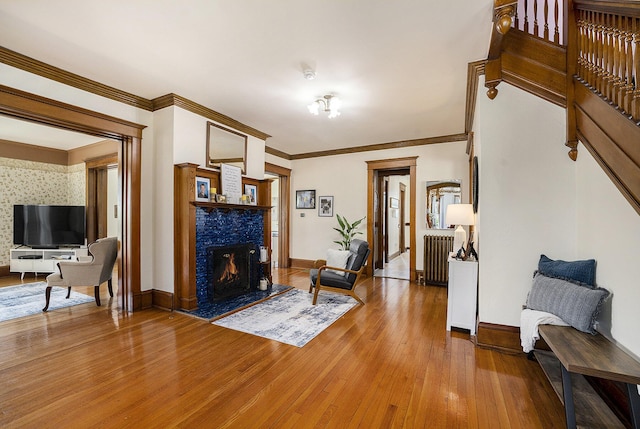 210 E St, Three Rivers, MI 49093 - living area featuring wood-type flooring, a lit fireplace, radiator heating unit, baseboards, and ornamental molding