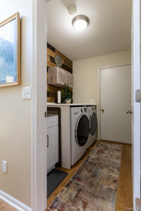 3163 W Ridge Ct, Commerce Twp, MI 48390 - laundry room with washing machine and clothes dryer, cabinet space, and light wood-style flooring