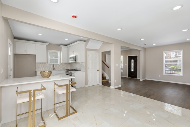 570 King St, Detroit, MI 48202 - kitchen with stainless steel appliances, a breakfast bar area, decorative backsplash, light countertops, and a peninsula