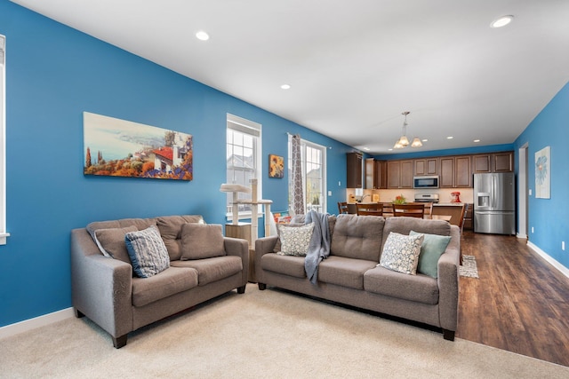 living room featuring a chandelier, recessed lighting, baseboards, and wood finished floors