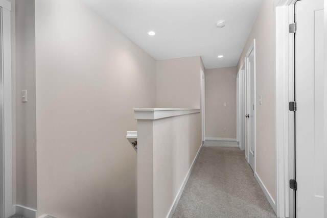 corridor featuring light colored carpet, baseboards, recessed lighting, and an upstairs landing