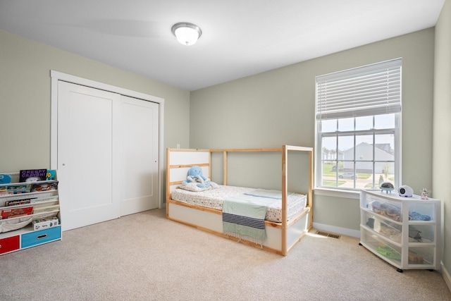 carpeted bedroom with a closet and baseboards