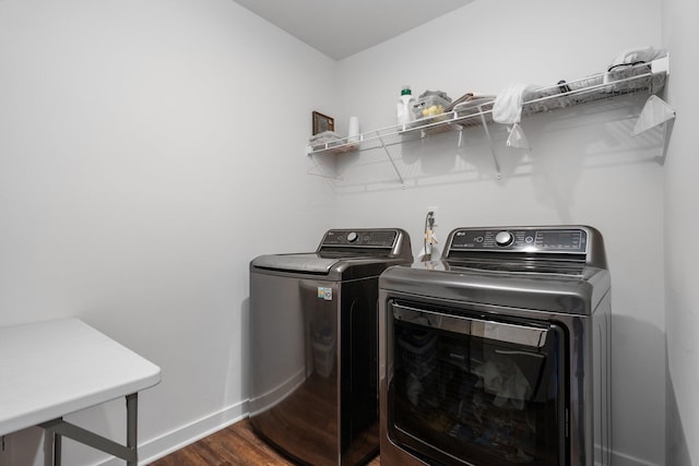 clothes washing area with baseboards, washer and dryer, and dark wood finished floors