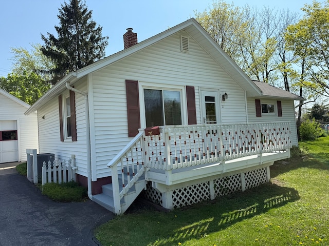 27 Turrill Ave, Lapeer, MI 48446 - rear view of house featuring a chimney, a lawn, a wooden deck, a garage, and cooling unit