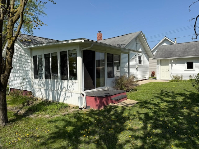 27 Turrill Ave, Lapeer, MI 48446 - rear view of house featuring a chimney, a lawn, a sunroom, and a shingled roof