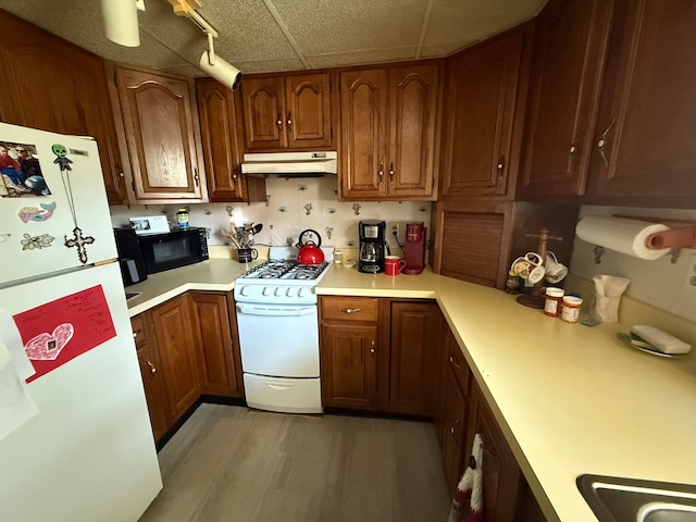 27 Turrill Ave, Lapeer, MI 48446 - kitchen featuring white appliances, under cabinet range hood, light countertops, brown cabinets, and light wood finished floors
