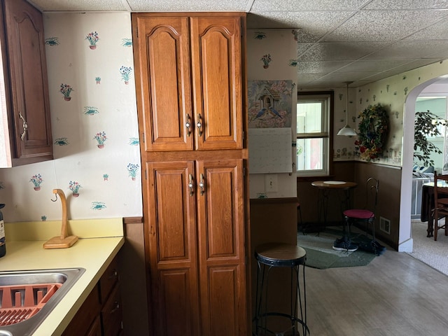 27 Turrill Ave, Lapeer, MI 48446 - kitchen featuring brown cabinetry, arched walkways, a drop ceiling, wood finished floors, and light countertops