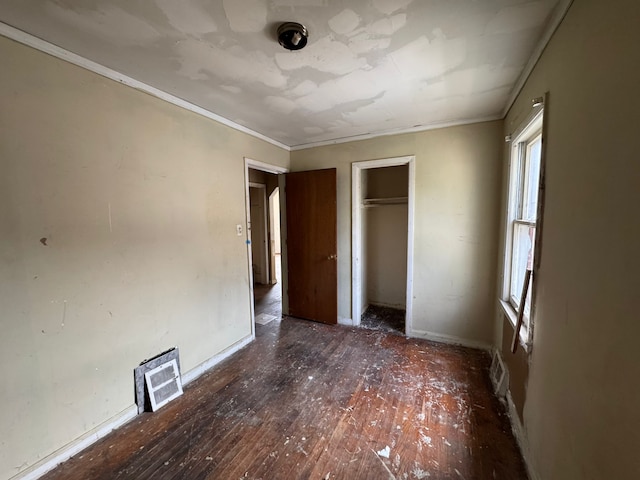 unfurnished bedroom featuring hardwood / wood-style floors, ornamental molding, a closet, and baseboards