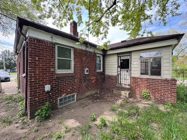 view of front of home with a chimney and brick siding