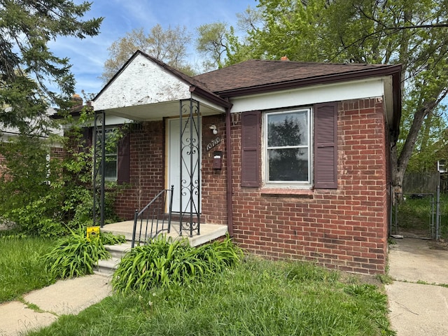 view of front of home featuring brick siding, roof with shingles, and fence