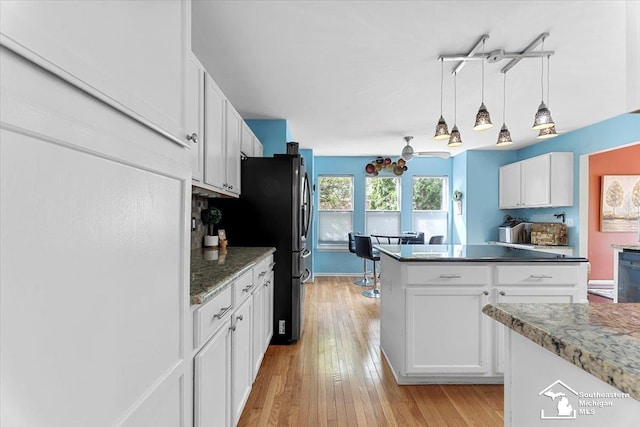 25345 Hunter Ln, Flat Rock, MI 48134 - kitchen with white cabinetry, light wood-style floors, hanging light fixtures, dark stone counters, and black dishwasher